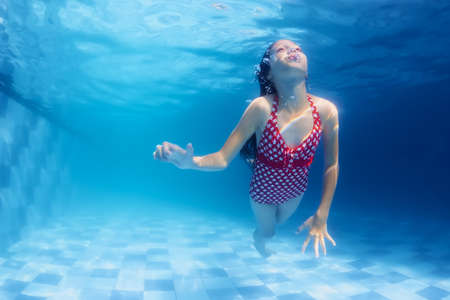 Child swimming underwater lesson  girl diving with fun in blue pool. Healthy active family lifestyle physical development and children water sports activity with parents on summer vacation with kidsの写真素材