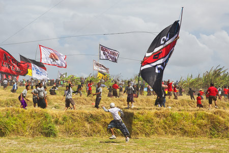 BALI, INDONESIA - 2012 JULY 15: Unidentified teenage boy running quickly away from dangerously falling big kite during Balinese people festival of traditional kites on the beach Galak in Bali islandのeditorial素材