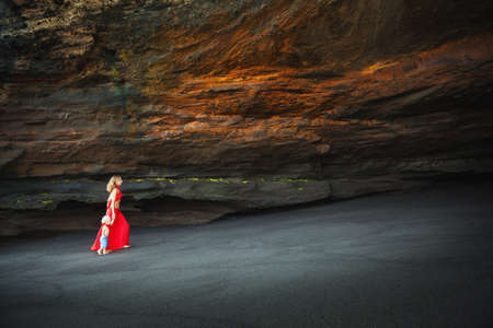 Beautiful mother with happy small baby son have fun walking in sea beach grotto. Healthy lifestyle, active parents, and outdoor activity with positive emotions on summer family vacation with childrenの写真素材