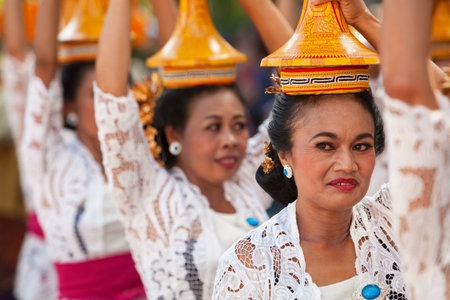 DENPASAR, BALI ISLAND, INDONESIA - JUNE 13, 2015: Group of beautiful women in traditional Balinese costumes carry on head religious offering for hindu ceremony on parade at art and culture festival.のeditorial素材