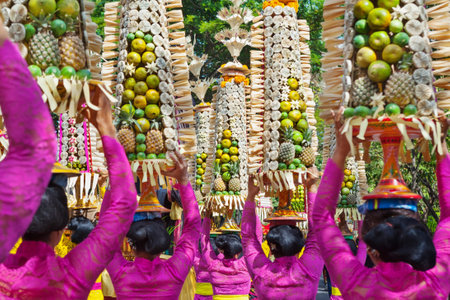 Procession of beautiful Balinese women in traditional costumes - sarong, carry offering on heads for Hindu ceremony. Arts festival, culture of Bali island and Indonesia people. Asian travel backgroundのeditorial素材