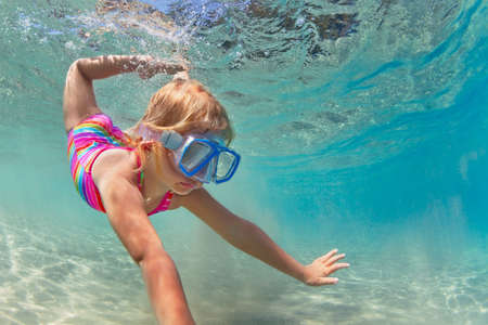 Happy baby girl in snorkeling mask dive underwater with fun in sea pool. Healthy lifestyle, people water sport outdoor adventure, swimming lessons on summer beach family holidays with childの写真素材