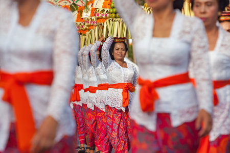 DENPASAR, BALI ISLAND, INDONESIA - JUNE 11, 2016: Group of beautiful women in traditional Balinese costumes carry on head religious offering for hindu ceremony on parade at art and culture festival.のeditorial素材