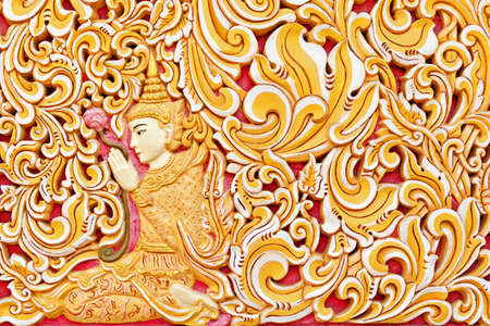 Wall exterior detail of ancient Burmese buddhist temple Dhammikarama in Georgetown on Penang island. Sitting in meditating pose Buddha hold in hand lotus flower. Asian arts, culture. Travel backgroundの写真素材