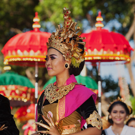 DENPASAR, BALI ISLAND, INDONESIA - JUNE 11, 2016: Beautiful woman dancer in bright traditional costume. Balinese people dancing on street parade at art and culture festival.のeditorial素材