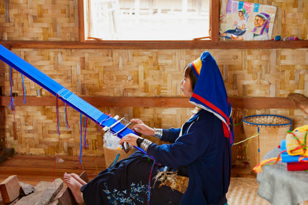 Inle Lake, Myanmar - January 04, 2007: Young woman of Kayan Lahwi (Padaung) people wearing brass coils on long neck weaving traditional Burmese handmade textile in village on Inle lake in Shan state.のeditorial素材