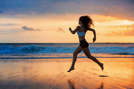 Barefoot sporty girl silhouette running along ocean surf by water pool to keep fit and health....
