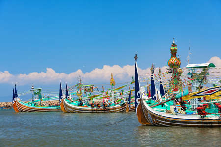 Traditional wooden fishing boats in Bugis style mooring in old fishers port on Bali island near...