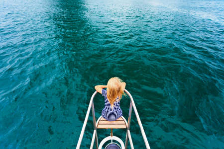 Joyful child portrait. Happy little baby girl on board of sailing yacht have fun discovering islands in tropical sea on summer coastal cruise. Travel adventure, yachting with kids on family vacation.の写真素材