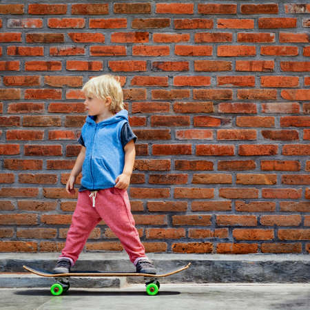 Little skater on skateboard have fun before children training class in skate park. Active family...