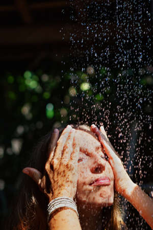 Attractive young girl takes shower. Woman stand under falling water drops in outside bathroom on...