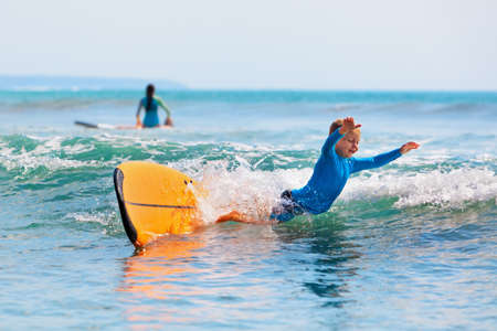 Happy boy - young surfer learning ride and fall from surfboard with fun. Active family lifestyle....