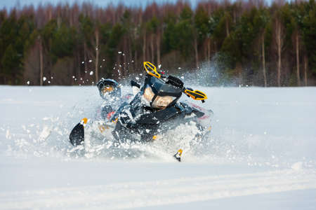 In snowdrift rider loss control and fall off from snowmobile. Reducing risk of injury by safety gear during backcountry tour accident. Extreme sport adventure, outdoor activity during winter holiday.の写真素材