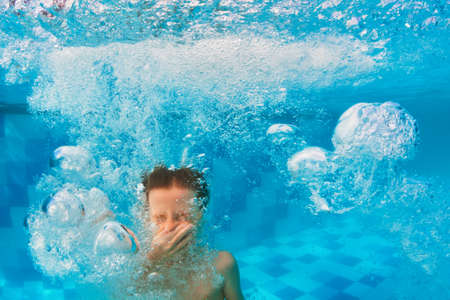 Happy family have fun in swimming pool. Funny child swim, dive in pool - jump deep down underwater from poolside. Healthy lifestyle, people water sport activity, swimming lessons on holidays with kidsの写真素材