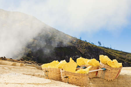 Heavy basket laden by pieces of natural sulfur to carry by miners from crater mine. Manual labour intensive sulphur mining operation in Kawah Ijen volcano. Popular travel destination in Java Indonesiaの写真素材