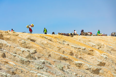 Java island, Indonesia - September 16, 2019: Basket laden by pieces of natural sulfur carrying by miner from crater mine. Extensive manual labour at sulphur mining operation in Kawah Ijen volcanoのeditorial素材