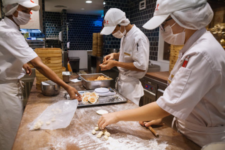 Johor, Malaysia - March 22, 2018: Asian chefs cooking traditional Chinese food in Taiwanese dumplings restaurant. Men cook and make fresh dough of steamed buns known as xiao long bao, mantou, dim sum.のeditorial素材