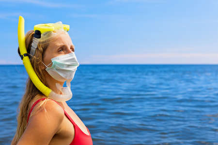 Girl in snorkeling mask wear surgical face mask on sea beach. Cancelled cruises, tours due coronavirus COVID 19 world epidemic. Travel ban for family vacation, tourism industry crisis at summer 2020の写真素材