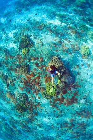 Happy family vacation. Man in snorkeling mask with camera dive underwater with tropical fishes in...