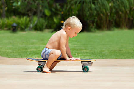 Funny skateboard riding. Little child with surf skateboard have fun in beach skate park. Active family lifestyle, outdoor activities on summer holidays in city. Kids recreational sports.の写真素材