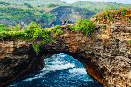 Family walk by natural bridge, look at natural sea pool Broken Bay. Popular Bali travel destination. Nusa Penida island day tour. Activity on beach holiday with kids.の写真素材