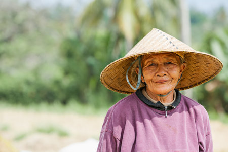 Ubud, Bali island, Indonesia - March 25, 2017: Indonesian farmer woman harvesting, winnowing rice grains in terraced rice field. Traditional rice plantations, agriculture in Balinese villages.のeditorial素材