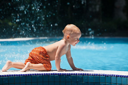 Funny photo of active baby splashing in swimming poolの写真素材