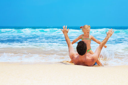 Father with daughter or grandfather with granddaughter play game with fun in sea surf on sea beach Active travel family lifestyle, water activity on summer holiday with child, babies and grandparentsの写真素材