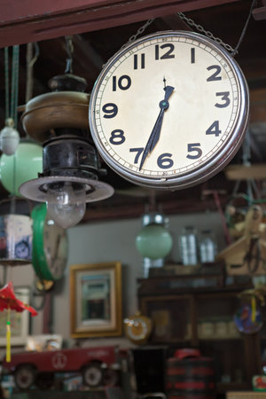 Vintage clock. Various vintage objects for sale at a indoor flea market. View of a display full of interesting old things for sale. Many groups of vintage assorted second-hand objects.の写真素材