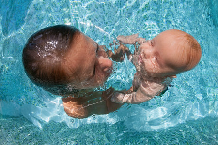 Happy people dive underwater with fun. Funny photo of mother, child in aqua park swimming pool. Family lifestyle, kids water sports activity, swimming lesson with parents on summer holidayの写真素材