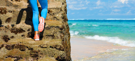 Young girl with slim body running up by stairs to keep fit and burning fat. Beach background with blue sky. Woman fitness, jogging sports activity and cardio exercises on summer family vacation.の写真素材
