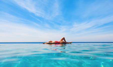 Happy girl have fun on summer beach holiday. Young woman relaxing at edge of infinity swimming pool with sea view from hill top. Healthy family lifestyle, summer travel with kids on tropical islands.の写真素材