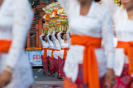 Denpasar, Bali island, Indonesia - June 11, 2016: Procession of beautiful Balinese women in traditional costumes - sarong, carry offering on heads for Hindu ceremony. Arts festival, culture of Bali.のeditorial素材