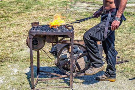 Detail shot of metal being worked by craftsman at a blacksmith forge in medieval scenery.