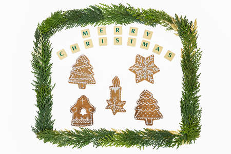 Homemade candlechristmas treesstarhouse in decoration gingerbread and honey cookies on christmas theme with a frame by pine tree twigs on white background with christmas wishes.の写真素材