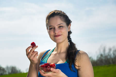 Smiling young woman eating fresh strawberries at the workout a healthy food for body .の写真素材
