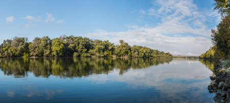 Early autumn landscape panorama with the river and a locomotive crossing the railway bridge .の写真素材