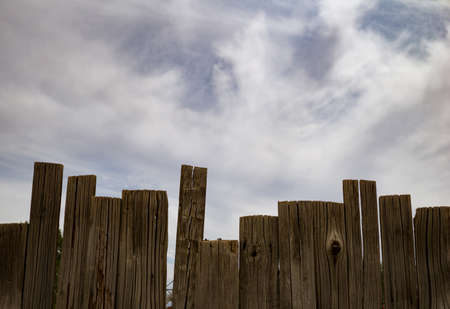 Old wooden fence against a blue cloudy skyの写真素材