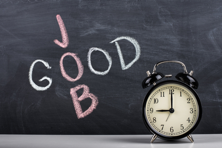 Retro alarm clock and text "good job" written with chalk on the blackboard.の写真素材