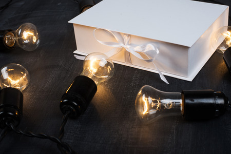 Gift Box and light bulbs to the dark backgroundの写真素材