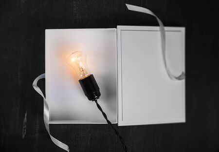 Gift Box and light bulbs to the dark backgroundの写真素材