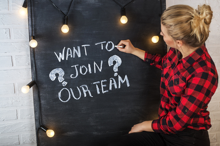 An attractive young woman with chalk at the blackboard. Want to join our team?の写真素材