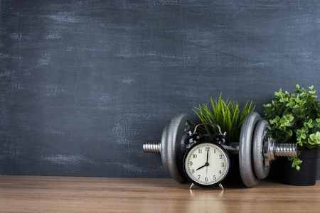 Dumbbell on a gray background and retro alarm clock. Time 8:00の写真素材