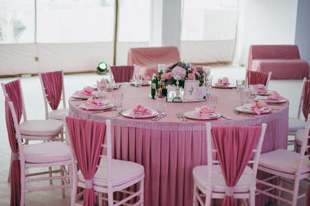 Wedding. Banquet. The chairs and table for guests, decorated with candles, served with cutlery and...