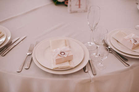 Wedding. Banquet. The chairs and table for guests, decorated with candles, served with cutlery and crockery and covered with a tablecloth. The table stands on a green lawn in the backyard banquet areaの写真素材
