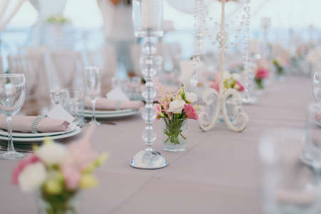 Wedding. Banquet. The chairs and table for guests, decorated with candles, served with cutlery and crockery and covered with a tablecloth. The table stands on a green lawn in the backyard banquet areaの写真素材