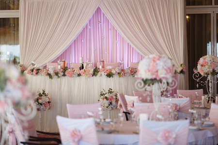 Wedding. Banquet. The chairs and table for guests, decorated with candles, served with cutlery and crockery and covered with a tablecloth. The table stands on a green lawn in the backyard banquet areaの写真素材