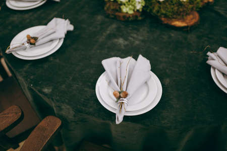 Wedding. Banquet. The chairs and table for guests, decorated with candles, served with cutlery and crockery and covered with a tablecloth. The table stands on a green lawn in the backyard banquet areaの写真素材