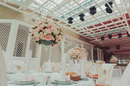 Wedding. Banquet. The chairs and table for guests, decorated with candles, served with cutlery and crockery and covered with a tablecloth. The table stands on a green lawn in the backyard banquet areaの写真素材