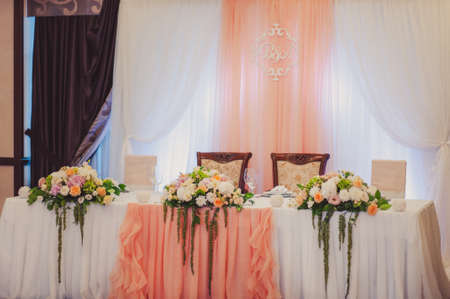 Wedding. Banquet. The chairs and table for guests, decorated with candles, served with cutlery and crockery and covered with a tablecloth. The table stands on a green lawn in the backyard banquet areaの写真素材